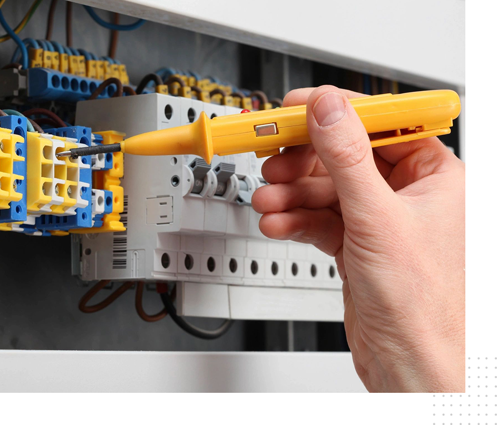 A person holding a yellow screwdriver in front of an electrical box.