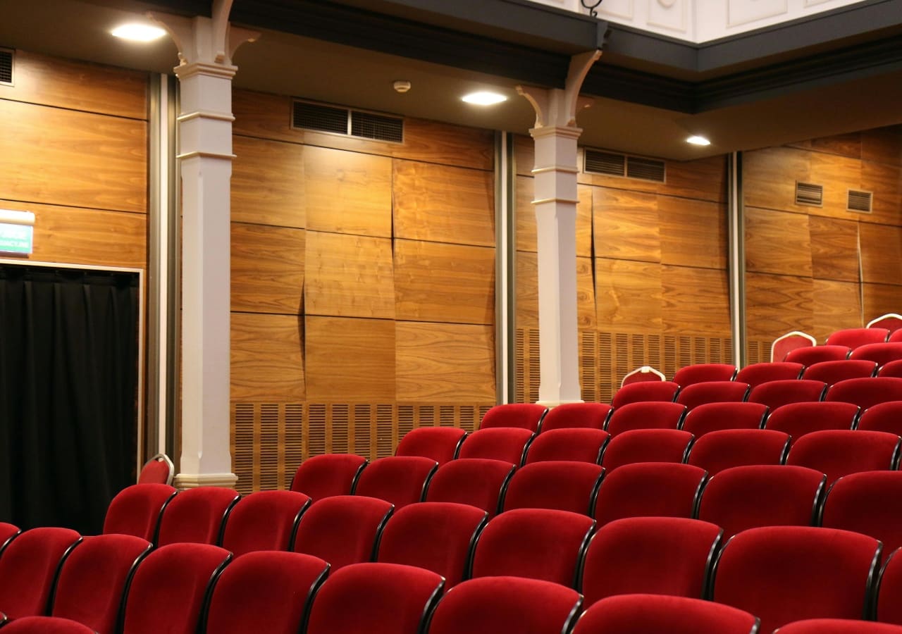 A large auditorium with red seats and pillars.